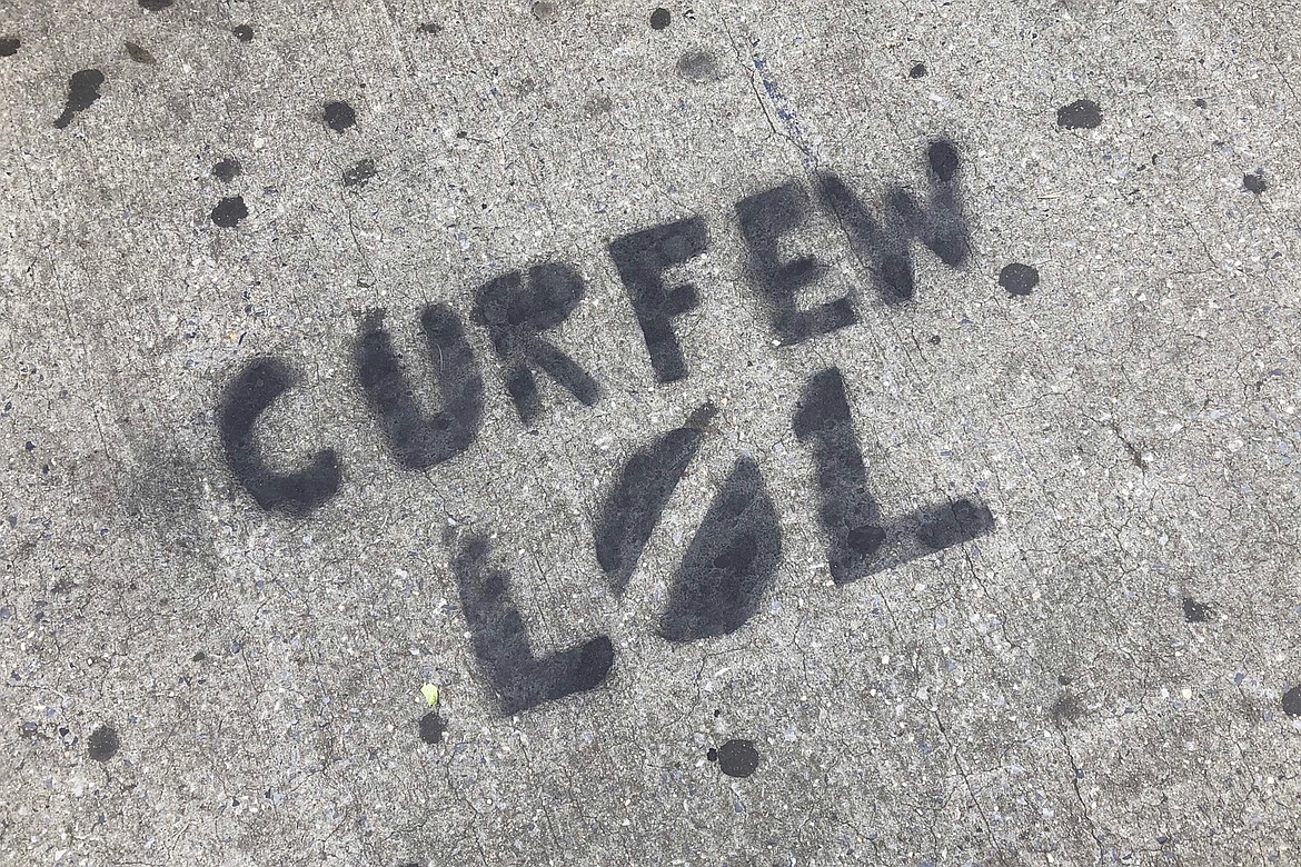 A sidewalk is spray painted with graffiti about New York City's curfew order, in the Brooklyn borough of New York, Tuesday, June 2, 2020. In New York City, nonviolent demonstrations against police brutality, sparked by the death of George Floyd at the hands of police in Minneapolis, were punctuated by people smashing storefront windows near Rockefeller Center and breaching the doors into the storied Macy's store, littering parts of Manhattan with broken glass.  (AP Photo/Mark Lennihan)