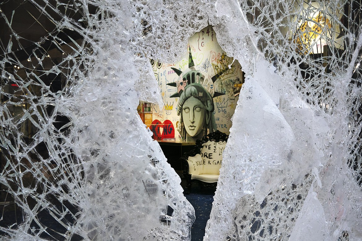 A Statue of Liberty painting is seen through a smashed Dolce and Gabbana store window, Monday, June 1, 2020, in the SoHo neighbourhood of New York. Protesters broke into the store Sunday night in reaction to George Floyd's death while in police custody on May 25 in Minneapolis. (AP Photo/Mark Lennihan)