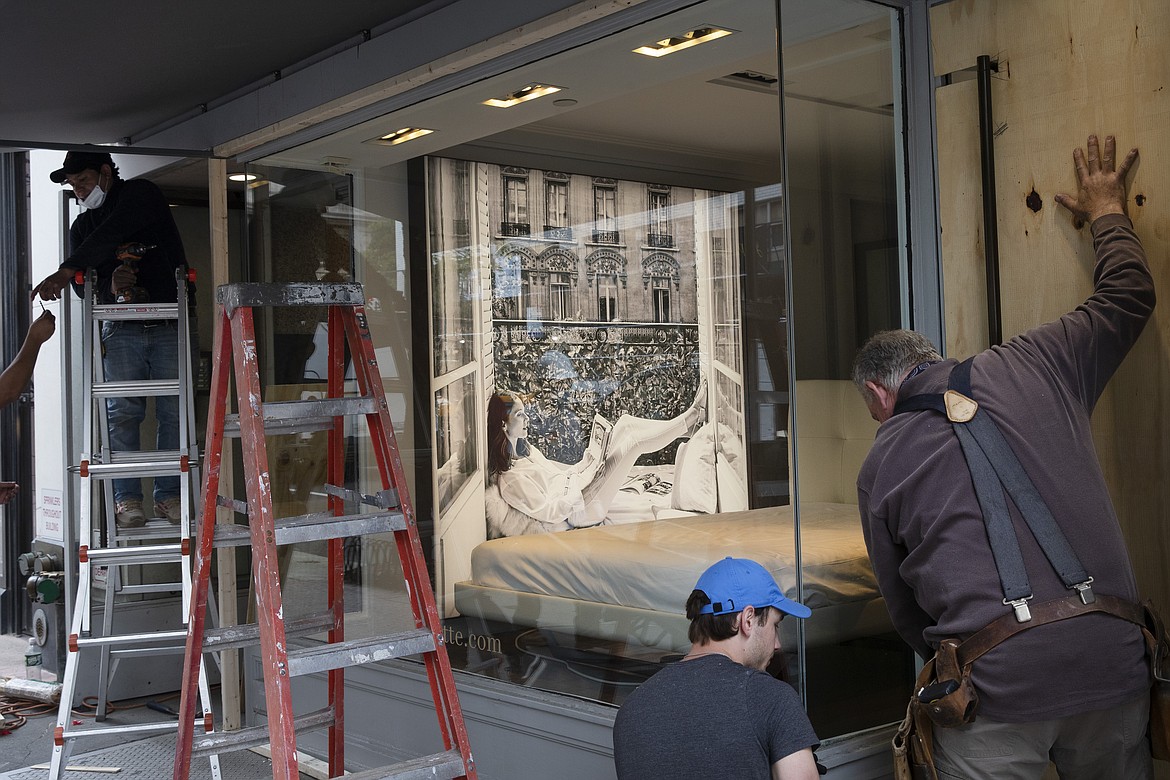 Workers protectively board up a store, Tuesday, June 2, 2020, on Madison Avenue in New York. Protesters broke nearby windows Monday night in reaction to George Floyd's death while in police custody on May 25 in Minneapolis.(AP Photo/Mark Lennihan)