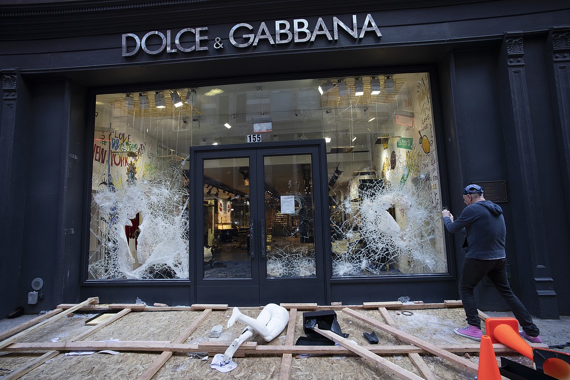 A passerby photographs a smashed Dolce and Gabbana store window in the SoHo neighbourhood of New York, Monday, June 1, 2020. Protesters broke into the store Sunday night in reaction to George Floyd's death while in police custody on May 25 in Minneapolis. (AP Photo/Mark Lennihan)
