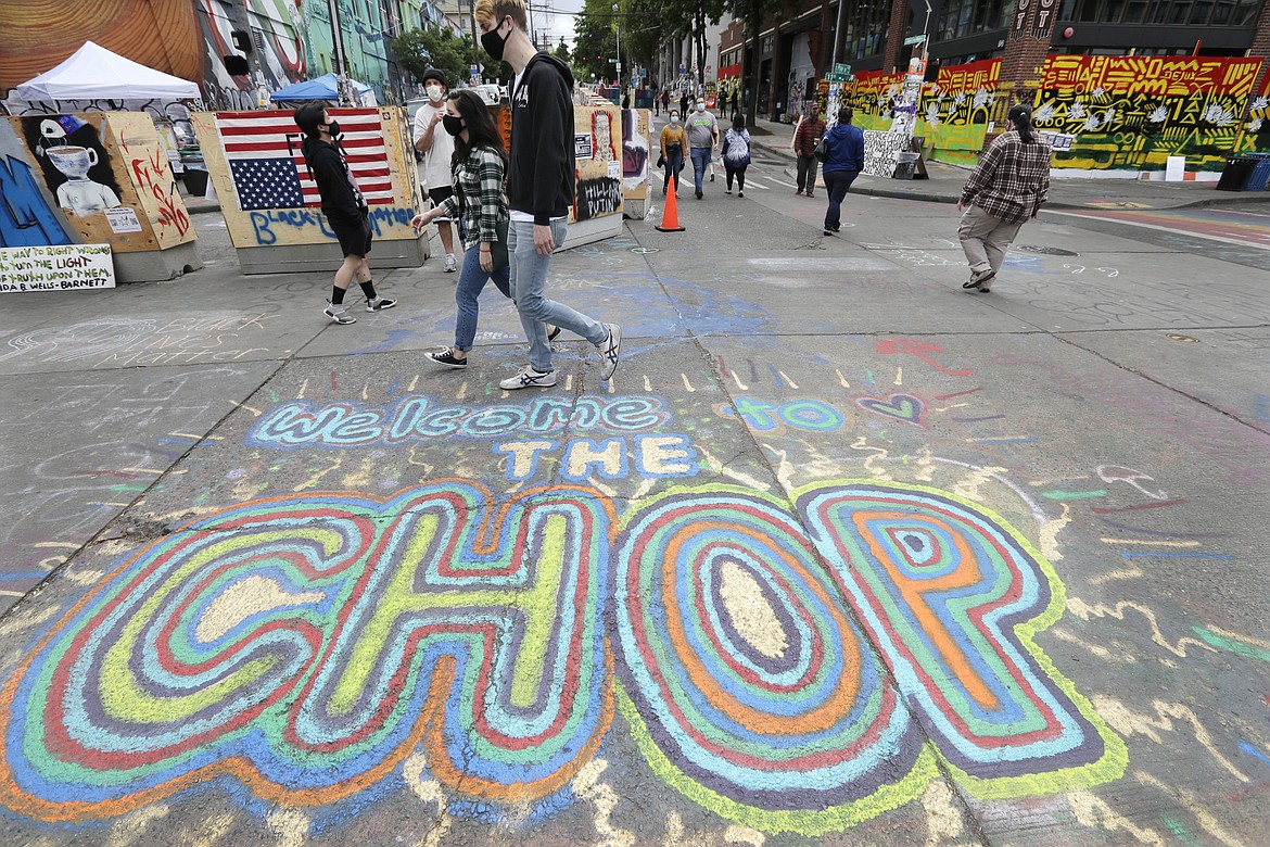 Pedestrians walk Sunday, June 21, 2020, in Seattle, where streets are blocked off in what has been named the Capitol Hill Occupied Protest (CHOP) zone. Police pulled back from several blocks of the city's Capitol Hill neighborhood near the Police Department's East Precinct building earlier in the month after clashes with people protesting the death of George Floyd. (AP Photo/Elaine Thompson)