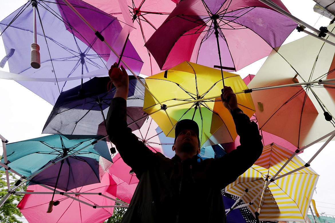 Protester Andrew Tomes adjusts umbrellas being used after a tarp was forgotten at a site supplying food and other essentials to demonstrators near a closed Seattle police precinct Tuesday, June 9, 2020, in Seattle, following protests over the death of George Floyd, a black man who was in police custody in Minneapolis. Under pressure from city councilors, protesters and dozens of other elected leaders who have demanded that officers dial back their tactics, the police department on Monday removed barricades near its East Precinct building in the Capitol Hill neighborhood, where protesters and riot squads had faced off nightly. Protesters were allowed to march and demonstrate in front of the building, and the night remained peaceful. (AP Photo/Elaine Thompson)