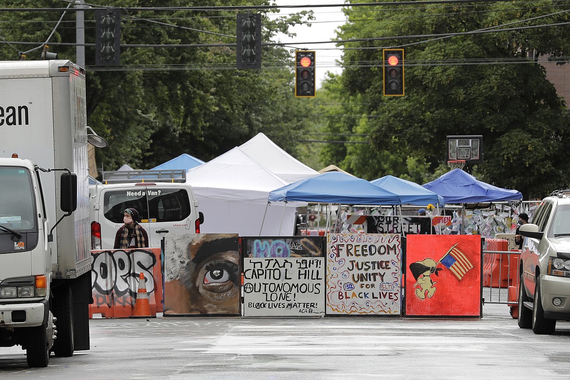 Signs are seen at an entrance, Monday, June 15, 2020, to what has been named the Capitol Hill Occupied Protest zone in Seattle. Protesters have taken over several blocks near downtown Seattle after officers withdrew from a police station in the area following violent confrontations. (AP Photo/Ted S. Warren)