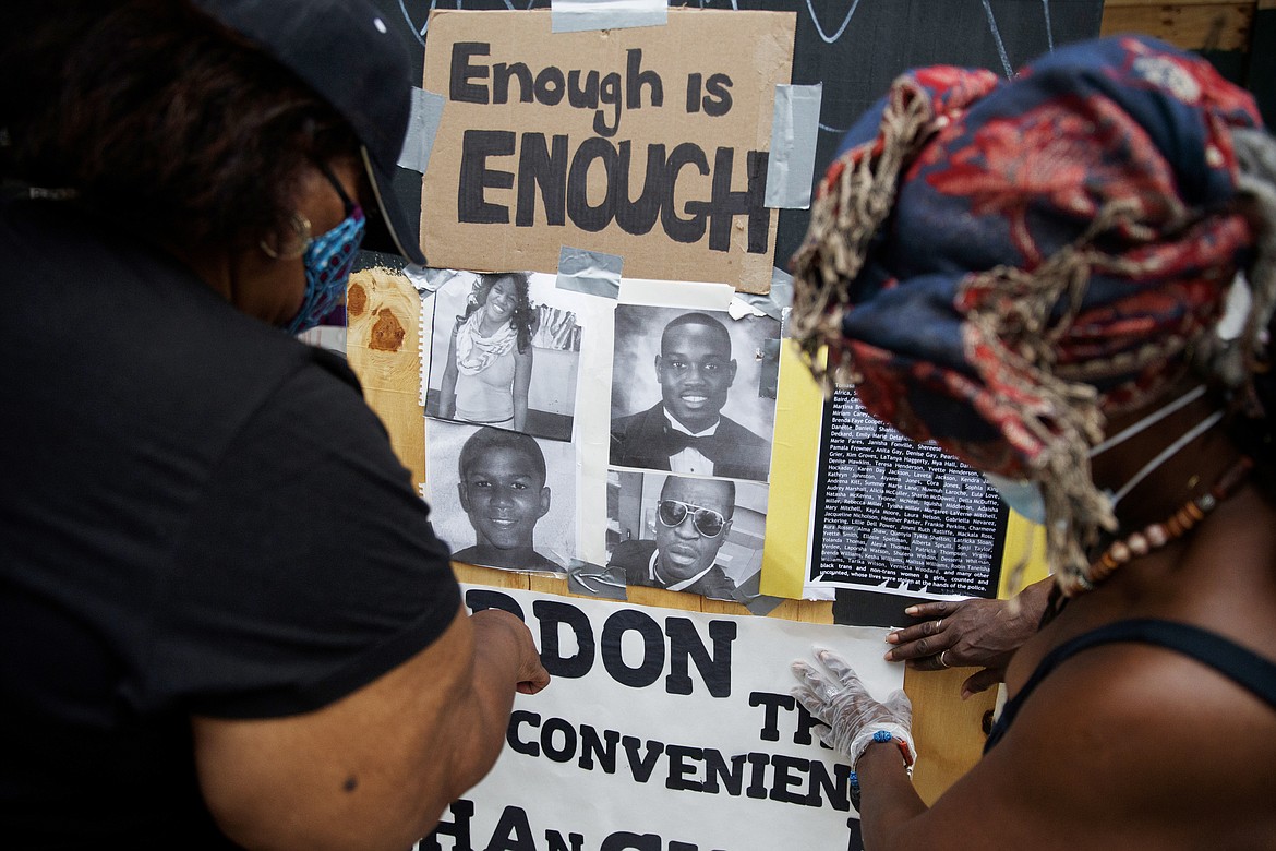 Wendy Long, left, and Sister Mamie, repost signs that were removed form the Lafayette Park parameter fence at the site of protests, Wednesday, June 10, 2020, near the White House in Washington. The protests began over the death of George Floyd, a black man who was in police custody in Minneapolis. Floyd died after being restrained by Minneapolis police officers. (AP Photo/Carolyn Kaster)