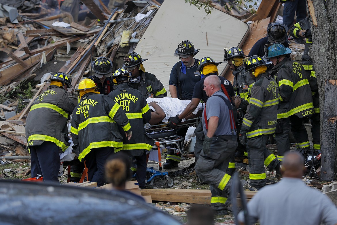 Baltimore City Fire Department carries a person out from the debris after an explosion in Baltimore on Monday, Aug. 10, 2020. Baltimore firefighters say an explosion has leveled several homes in the city. (AP Photo/Julio Cortez)