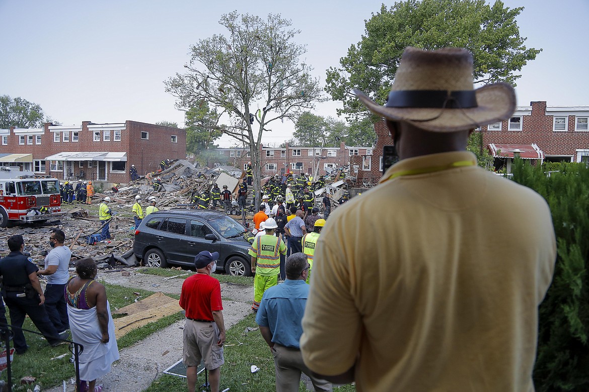 People gather outside an explosion in Baltimore on Monday, Aug. 10, 2020. Baltimore firefighters say an explosion has leveled several homes in the city. (AP Photo/Julio Cortez)