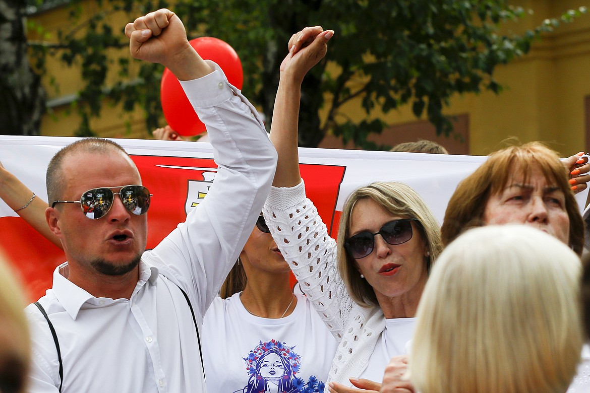 People shout a slogan "release (from prison)" to show their solidarity with the detainees at a detention center during opposition rally in Minsk, Belarus, Tuesday, Aug. 18, 2020. After the police crackdown at least 7,000 were detained by riot police, with many complaining they were beaten mercilessly. (AP Photo/Sergei Grits)