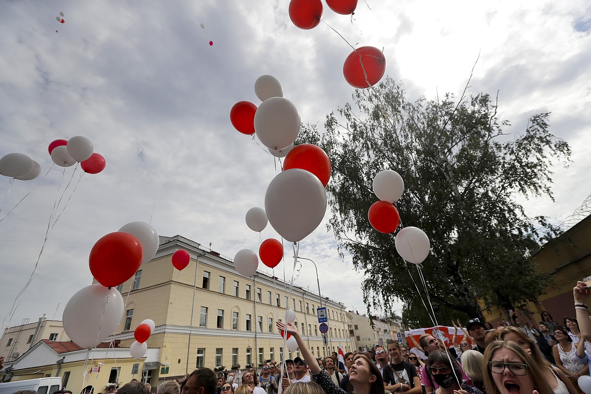 People shout a slogan "release (from prison)" to show their solidarity with the detainees and people release balloons in colors of old Belarusian national flag into the sky at a detention center during opposition rally in Minsk, Belarus, Tuesday, Aug. 18, 2020. After the police crackdown at least 7,000 were detained by riot police, with many complaining they were beaten mercilessly. (AP Photo/Sergei Grits)