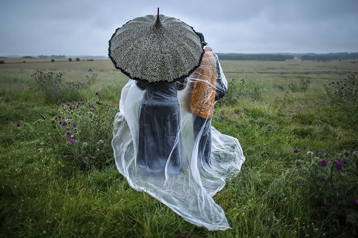 People shield from the rain next to the closed Stonehenge as people gather to celebrate the Summer Solstice, the longest day of the year, near Salisbury, England, Sunday June 21, 2020. (Ben Birchall/PA via AP)