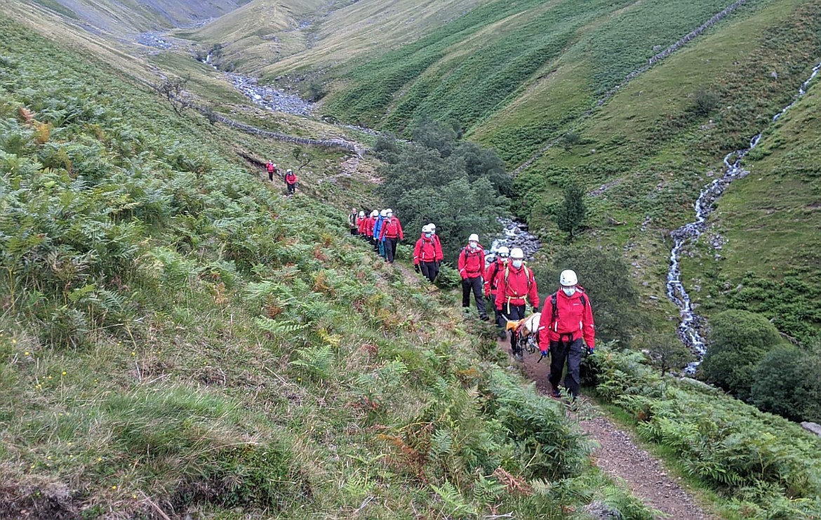 Volunteers from Wasdale mountain rescue team take turns to carry 121lb (55kg) St Bernard dog, Daisy from England's highest peak, Scafell Pike, Sunday July 26, 2020. The mountain rescue team spent nearly five hours rescuing St Bernard dog Daisy, who had collapsed displaying signs of pain in her rear legs and was refusing to move, while descending Scafell Pike. The Wasdale Mountain Rescue team rely on public contributions to their JustGiving.com/wasdalemrt page to fund their mountain safety efforts. (Wasdale Mountain Rescue via AP)