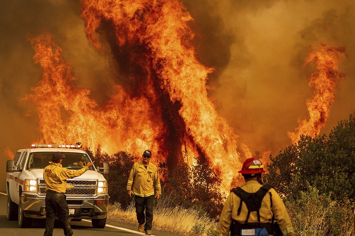 Flames from the LNU Lightning Complex fires leap above Butts Canyon Road on Sunday, Aug. 23, 2020, as firefighters work to contain the blaze in unincorporated Lake County, Calif. (AP Photo/Noah Berger)