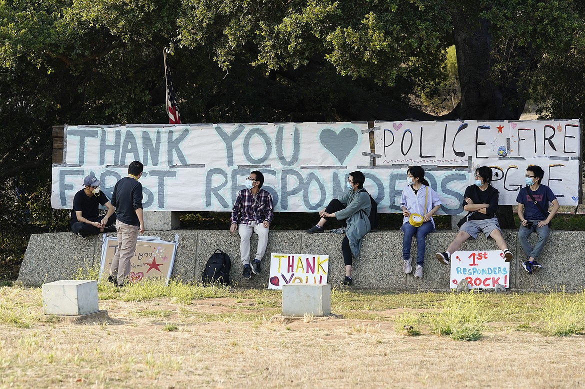 Students and researchers at UC Santa Cruz sit in front of a sign thanking first responders for their efforts in fighting the CZU August Lightning Complex Fire Monday, Aug. 24, 2020, in Santa Cruz, Calif. (AP Photo/Marcio Jose Sanchez)