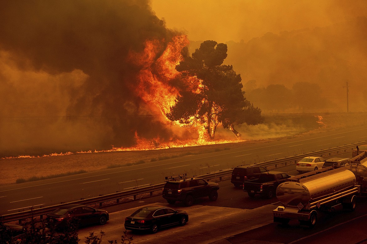 Flames from the LNU Lightning Complex fires jump Interstate 80 in Vacaville, Calif., Wednesday, Aug. 19, 2020. The highway was closed in both directions shortly afterward. Fire crews across the region scrambled to contain dozens of wildfires sparked by lightning strikes as a statewide heat wave continues. (AP Photo/Noah Berger)