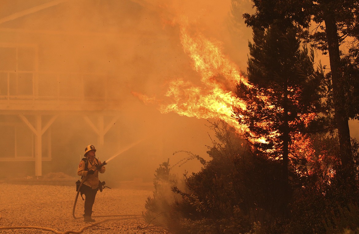 Firefighter David Widaman directs water onto a tree that had exploded in flame as a fire crew defends a house northwest of Santa Cruz, Calif., Wednesday Aug. 19, 2020. (Shmuel Thaler/The Santa Cruz Sentinel via AP)