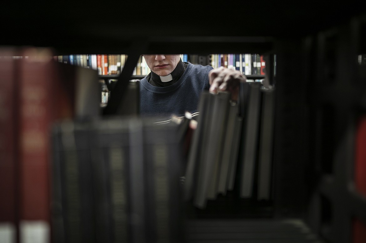 ADVANCE FOR SUNDAY, FEB 16 - Shane Flanagan returns a book to the shelf in the library at St. Charles Borromeo Seminary in Wynnewood, Pa., on Wednesday, Feb. 5, 2020. The seminary is preparing to move after the sale of its campus. (AP Photo/Wong Maye-E)