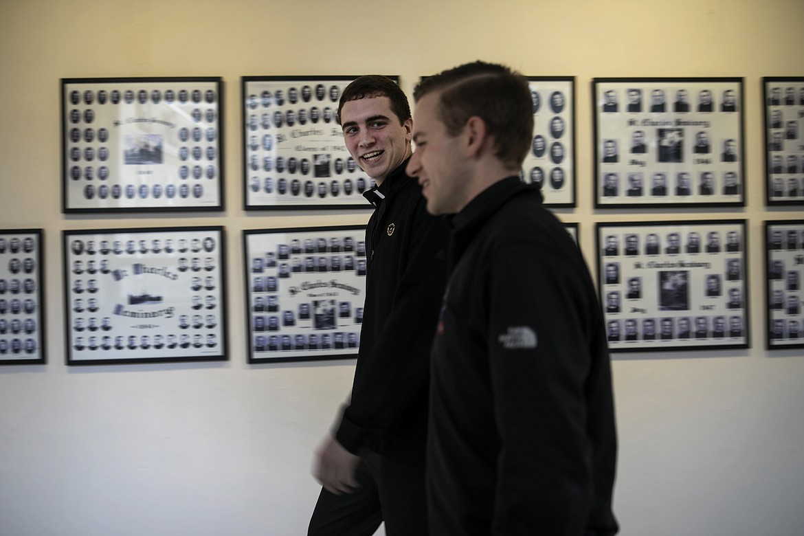 ADVANCE FOR SUNDAY, FEB 16 - Seminarians John Paul Heisler, left, and Daniel Rice walk past photos of prior classes of graduates at St. Charles Borromeo Seminary in Wynnewood, Pa., on Wednesday, Feb. 5, 2020. Despite crises in the Catholic Church, enrollment at U.S. seminaries remains relatively steady. (AP Photo/Wong Maye-E)