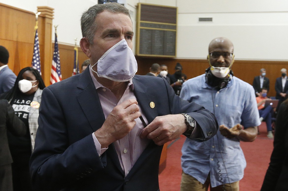 Virginia Gov. Ralph Northam, left, dons a mask as he leaves a news conference after announcing his plans to remove the statue of Confederate General Robert E. Lee on Monument Avenue Thursday June 4, 2020, in Richmond, Va. (AP Photo/Steve Helber)