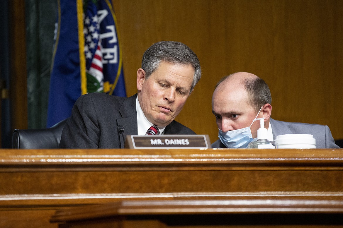 FILE - In this Tuesday, June 2, 2020 file photo Sen. Steve Daines, R-Mont., speaks to a member of his staff during a Senate Finance Committee hearing on the FDA foreign drug manufacturing inspection process on Capitol Hill in Washington. Daines is seeking a second term and faces Montana Gov. Steve Bullock in the Nov. 3, 2020 election. (Stefani Reynolds/Pool via AP,File)