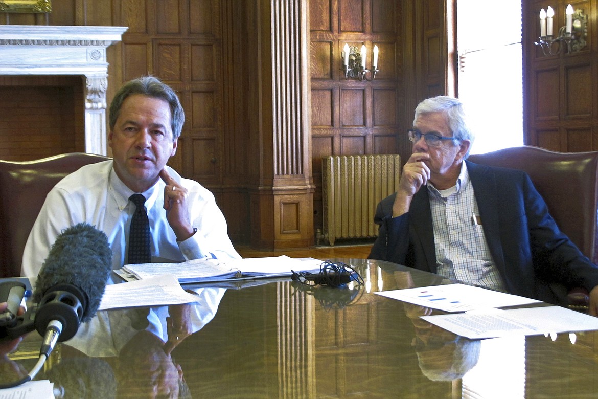 FILE - In this July 25, 2018 file photo, Montana Gov. Steve Bullock, left, talks about restoring some state budget cuts as Lt. Gov. Mike Cooney looks on in Helena, Mont. The battle against the coronavirus is giving Cooney an unexpected boost as he faces a well-financed opponent with extensive political connections in the June 2, 2020 Democratic primary for governor. (AP Photo/Matt Volz, File)