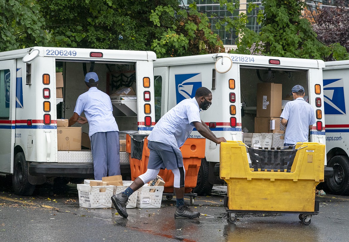 FILE - In this July 31, 2020, file photo, letter carriers load mail trucks for deliveries at a U.S. Postal Service facility in McLean, Va. The success of the 2020 presidential election could come down to a most unlikely government agency: the U.S. Postal Service.  (AP Photo/J. Scott Applewhite, File)