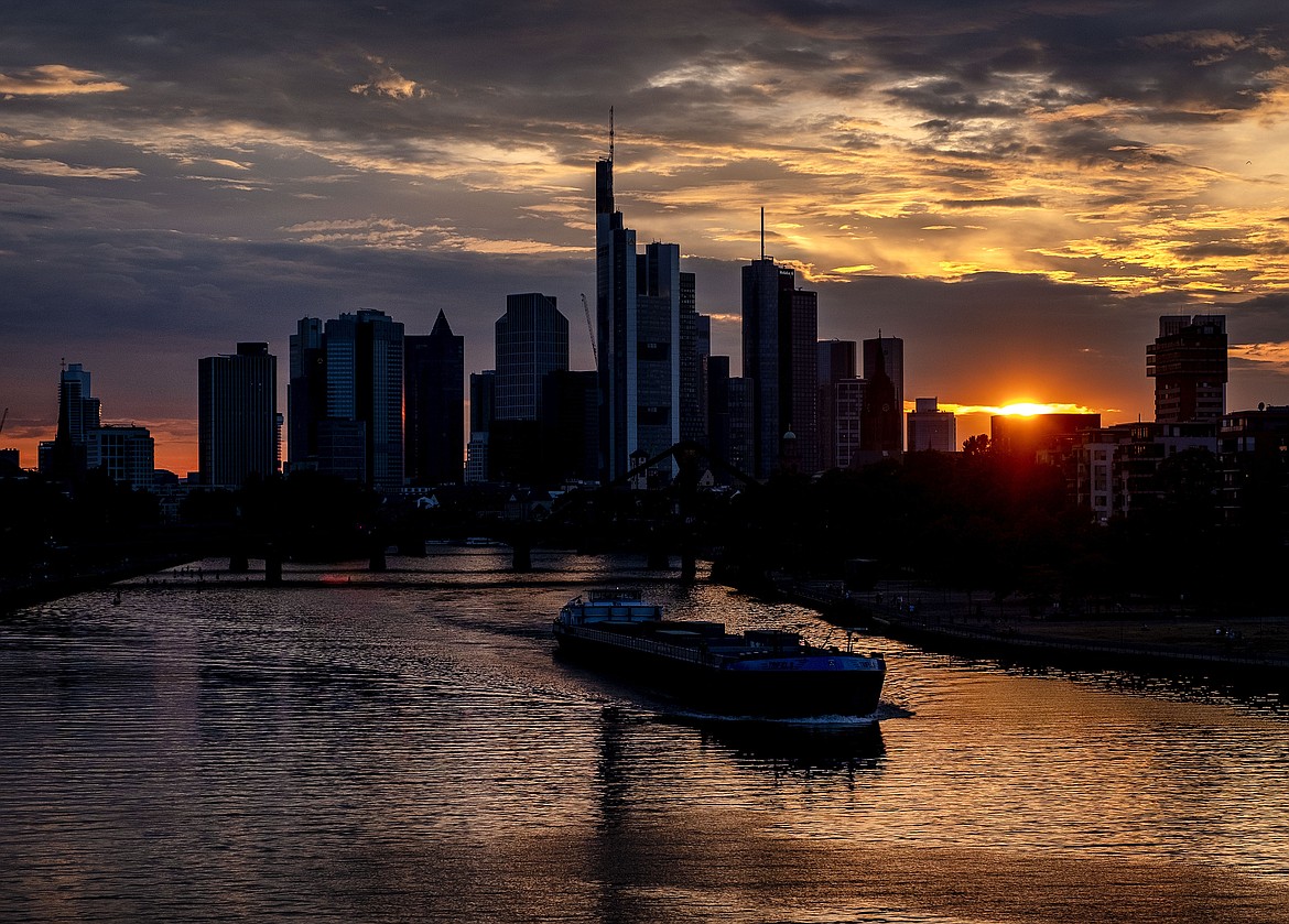 A cargo vessel cruises on the river Main with the buildings of the banking district in background in Frankfurt, Germany, after sunset on Friday, Aug. 14, 2020. (AP Photo/Michael Probst)