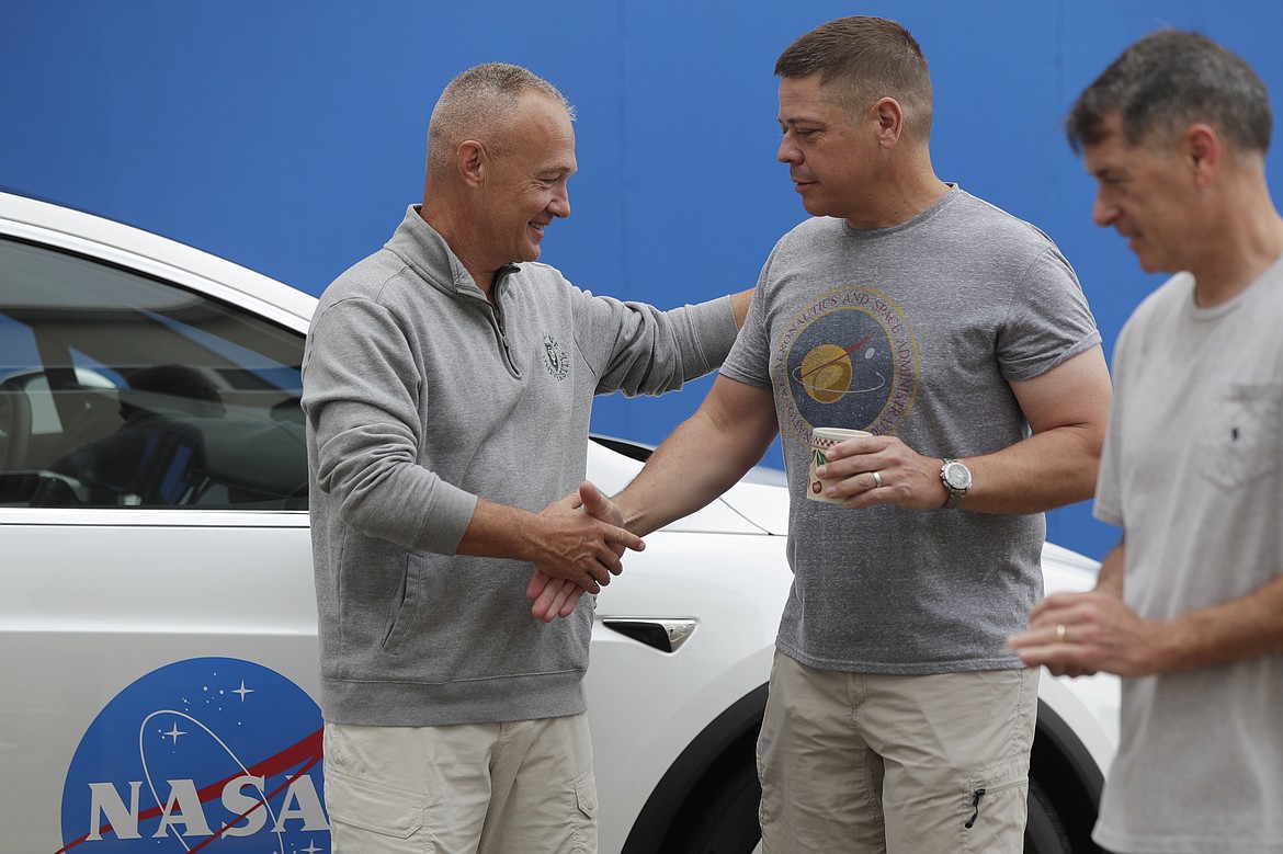 NASA astronauts Douglas Hurley, left, and Robert Behnken shake hands outside the Neil A. Armstrong Operations and Checkout Building, at the Kennedy Space Center in Cape Canaveral, Fla., Wednesday, May 27, 2020. The two astronauts will fly on a SpaceX test flight to the International Space Station. For the first time in nearly a decade, astronauts will blast into orbit aboard an American rocket from American soil, a first for a private company. (AP Photo/John Raoux)