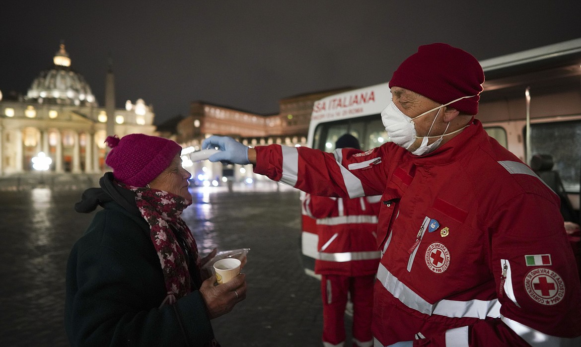 A red cross volunteer checks the temperature of a homeless woman, in front of St. Peter’s Square, in Rome. (AP Photo)