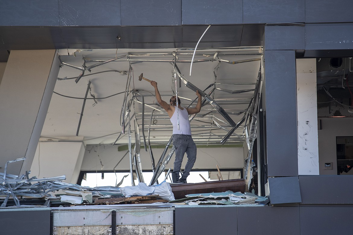 A man removes debris from a damaged building near the site of the Aug. 4 explosion that killed more than 170 people, injured thousands and caused widespread destruction, in Beirut, Lebanon, Friday, Aug. 14, 2020. (AP Photo/Hassan Ammar)