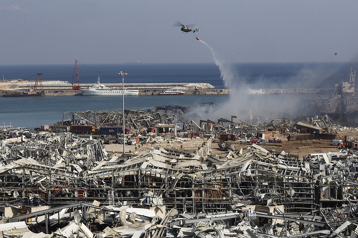 A Lebanese army helicopter throw water at the scene where an explosion hit the seaport of Beirut, Lebanon, Wednesday, Aug. 5, 2020. Residents of Beirut awoke to a scene of utter devastation on Wednesday, a day after a massive explosion at the port sent shock waves across the Lebanese capital, killing at least 100 people and wounding thousands. (AP Photo/Hussein Malla)