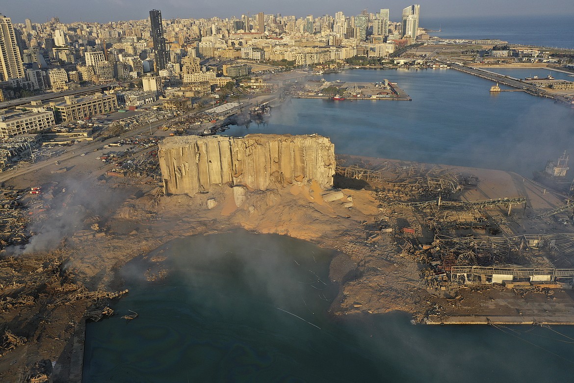 FILE - In this August 5, 2020 file photo, smoke rises from the scene of an explosion that hit the seaport of Beirut, Lebanon.  Lebanon’s judicial investigation of the Beirut port explosion started with political wrangling over the naming of a lead investigator, military threats to jail leakers and doubts over whether a panel appointed along sectarian lines could be fully impartial. So for many Lebanese, their greatest hope for credible answers about the blast that wrecked much of their capital lies with outsiders.   (AP Photo/Hussein Malla, File)