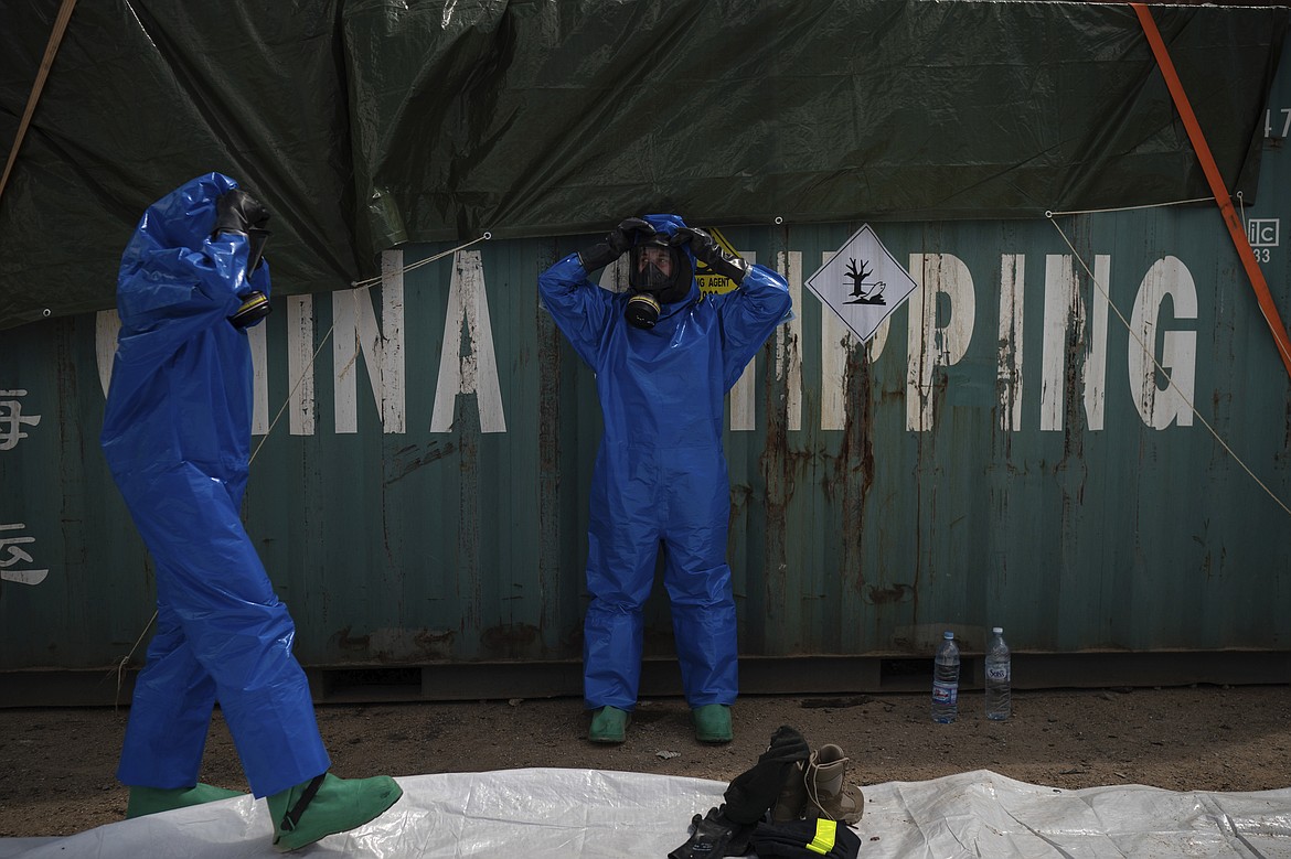 FILE - In this August 10, 2020 file photo, French emergency workers, part of a special unit working with chemicals, suit up near the site of last week's explosion, in the port of Beirut, Lebanon.  For many Lebanese, their greatest hope for credible answers about the blast that wrecked much of their capital lies with outsiders.  (AP Photo/Felipe Dana, File)