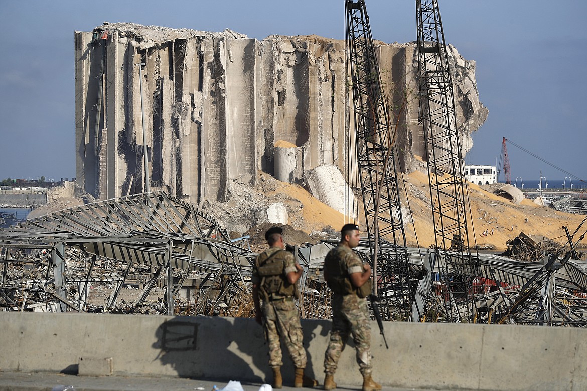 FILE - In this August 6, 2020 file photo, Lebanese army soldiers stand guard at the scene where an explosion hit on Tuesday the seaport of Beirut, Lebanon. Lebanon's judicial investigation of the Beirut port explosion started with political wrangling over the naming of a lead investigator, military threats to jail leakers and doubts over whether a panel appointed along sectarian lines could be fully impartial. (AP Photo/Hussein Malla, File)