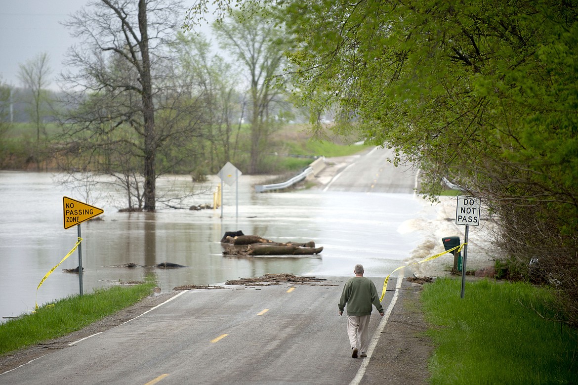Freeland resident Cyndi Ballien walks up to get a closer look as heavy rain floods North Gleaner Road near its intersection with Tittabawassee Road on Tuesday, May 19, 2020, in Saginaw County, Mich. People living along two mid-Michigan lakes and parts of a river were evacuated Tuesday following several days of heavy rain that produced flooding and put pressure on dams in the area. (Jake May/The Flint Journal via AP)