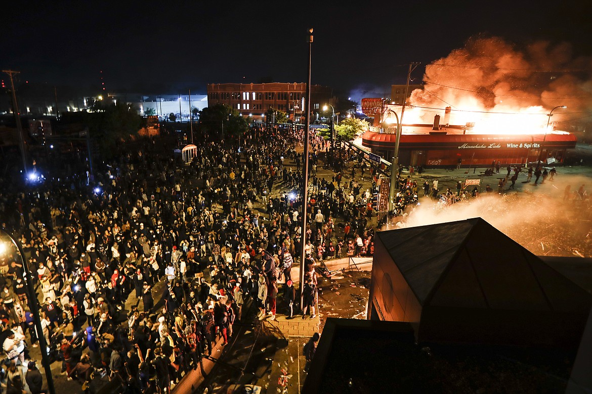 Protestors demonstrate outside of a burning Minneapolis 3rd Police Precinct, Thursday, May 28, 2020, in Minneapolis. Protests over the death of George Floyd, a black man who died in police custody Monday, broke out in Minneapolis for a third straight night. (AP Photo/John Minchillo)