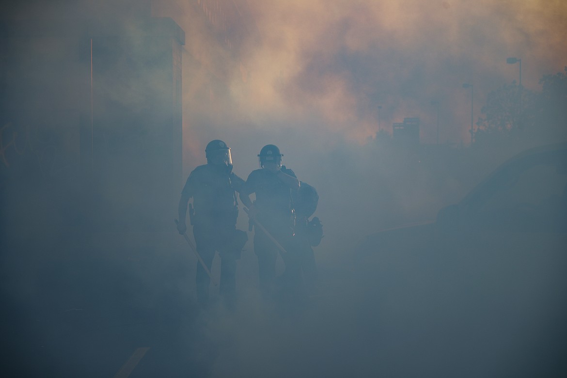 Police officers walk through a cloud of tear gas, Thursday, May 28, 2020, in St. Paul, Minn. Protests over the death of George Floyd, a black man who died in police custody Monday, broke out in Minneapolis for a third straight night. (AP Photo/John Minchillo)