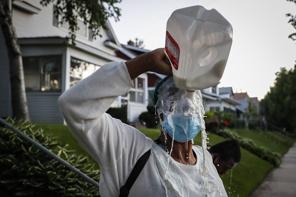A protestor douses her face with milk after being exposed to tear gas fired by police, Thursday, May 28, 2020, in St. Paul, Minn. Protests over the death of George Floyd, a black man who died in police custody Monday, broke out in Minneapolis for a third straight night. (AP Photo/John Minchillo)