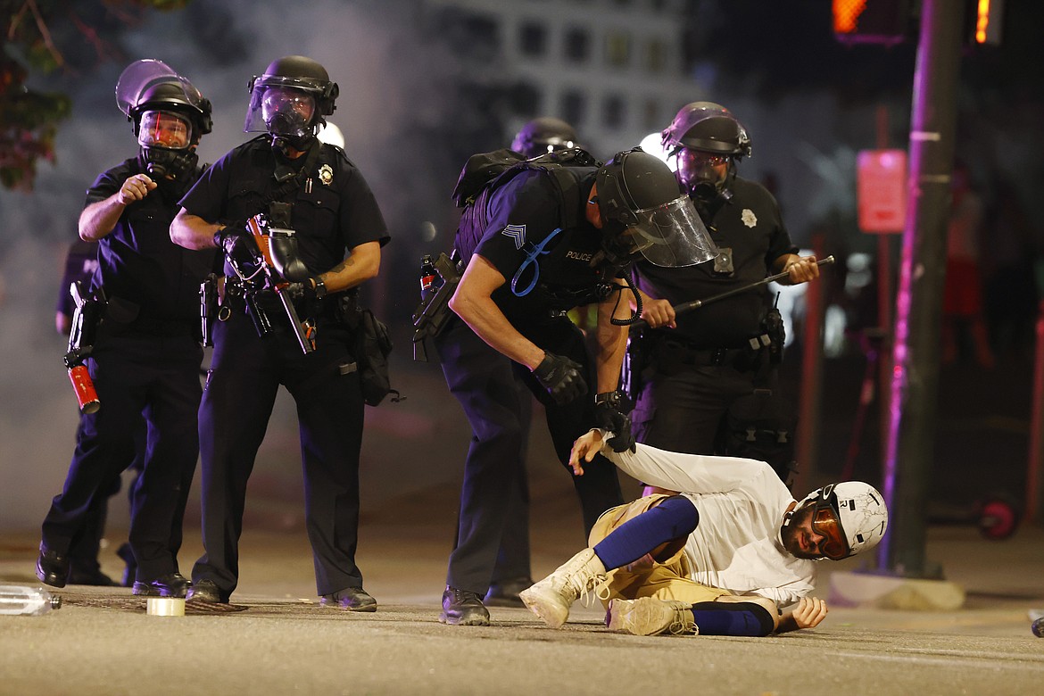 Denver Police Department officers clear a man who fell to the street after they used tear gas and rubber bullets to disperse a protest outside the State Capitol over the death of George Floyd, a handcuffed black man who died in police custody in Minneapolis, late Thursday, May 28, 2020, in Denver. (AP Photo/David Zalubowski)