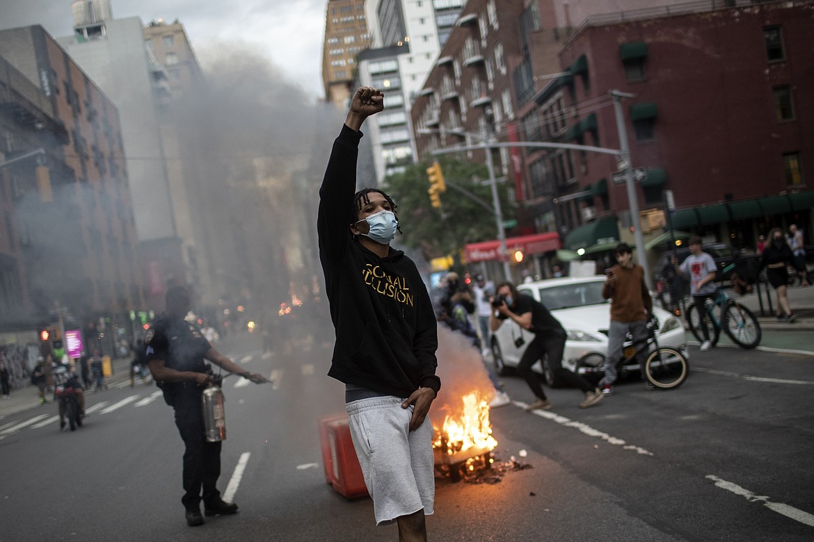 Protesters march down the street as thrash burns in the background during a solidarity rally for George Floyd, Saturday, May 30, 2020, in New York. Protests were held throughout the city over the death of Floyd, a black man in police custody in Minneapolis who died after being restrained by police officers on Memorial Day. (AP Photo/Wong Maye-E)