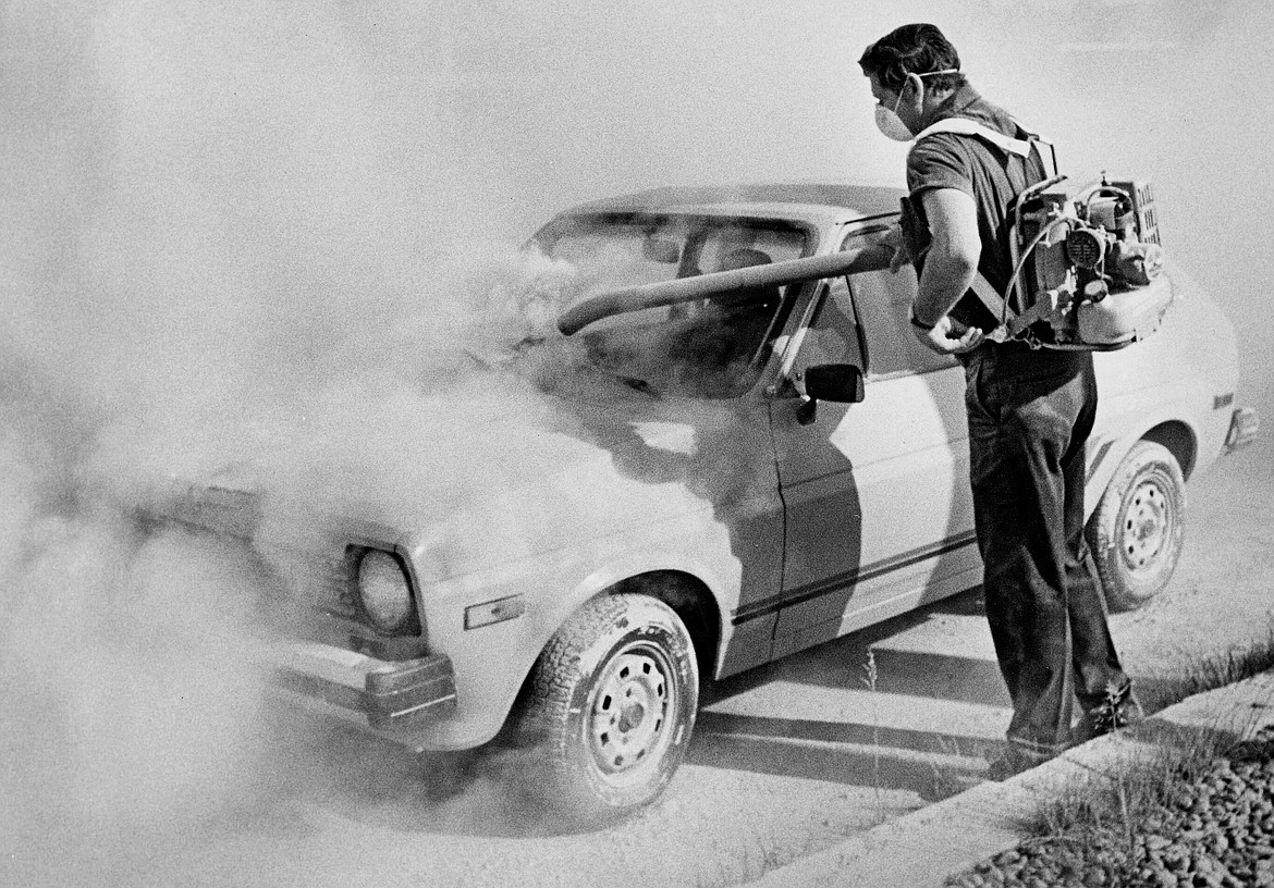 FILE - In this 1980 file photo, a worker at an auto dealership in Moscow, Idaho, uses a blower to remove ash from the eruption of Mount St. Helens  from a car in Washington state, more than 350 miles away. May 18, 2020, will mark the 40th anniversary of the eruption of the volcano. (Moscow-Pullman Daily News via AP, File)