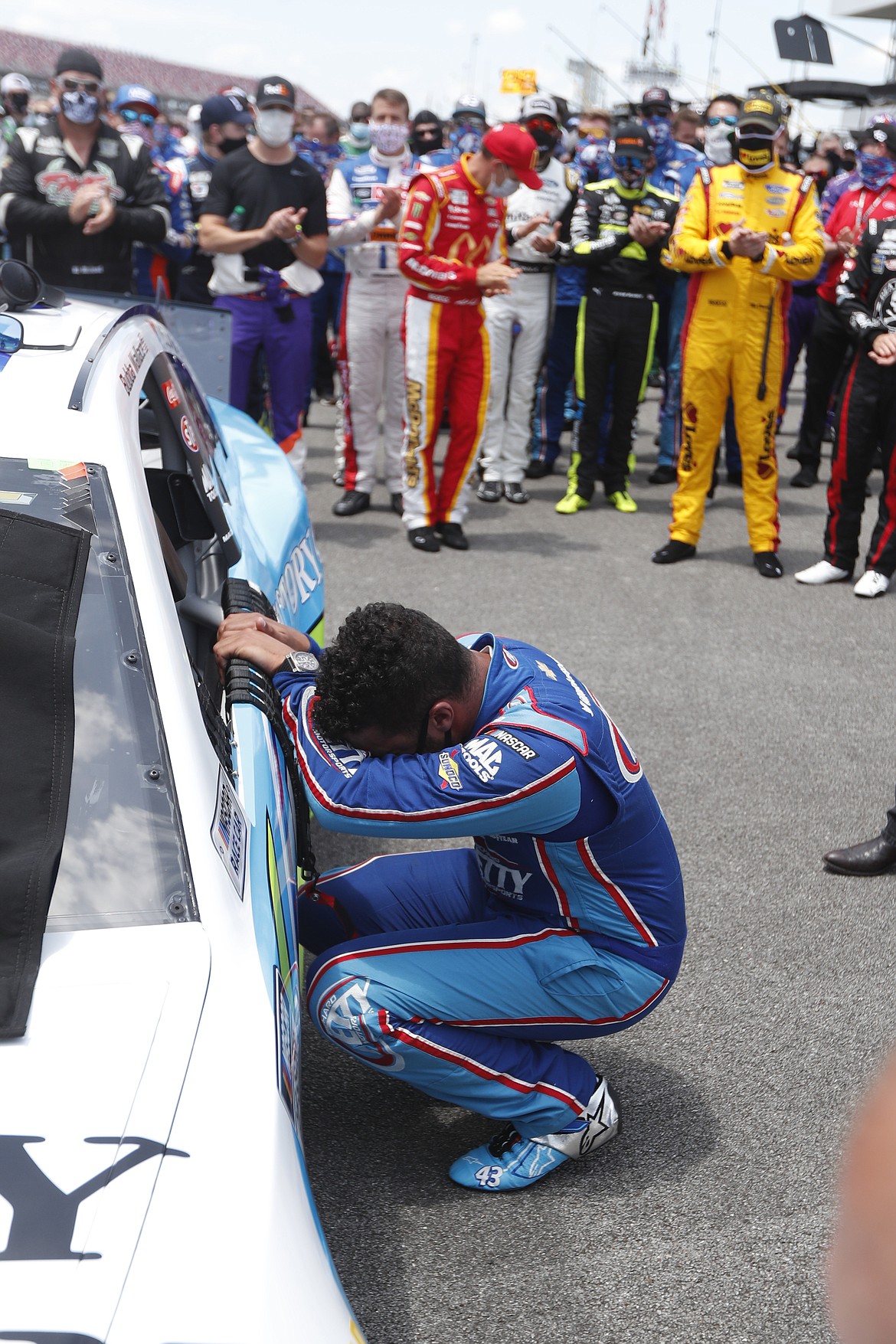 Driver Bubba Wallace, front, is overcome with emotion as he arrives at his car in the pits of the Talladega Superspeedway prior to the start of the NASCAR Cup Series auto race at the Talladega Superspeedway in Talladega Ala., Monday June 22, 2020. In an extraordinary act of solidarity with NASCAR’s only Black driver, dozens of drivers pushed the car belonging to Bubba Wallace to the front of the field before Monday’s race as FBI agents nearby tried to find out who left a noose in his garage stall over the weekend. (AP Photo/John Bazemore)