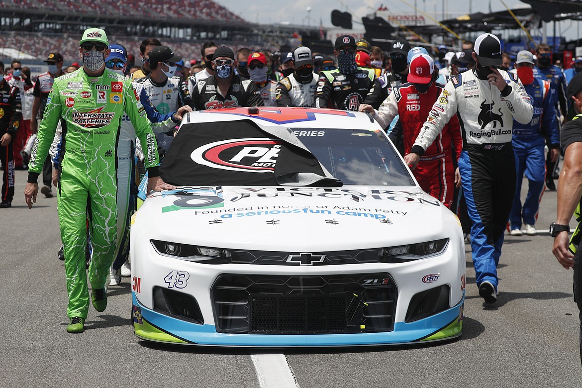 Nascar drivers Kyle Busch, left, and Corey LaJoie, right, join other drivers and crews as they push the car of Bubba Wallace to the front of the field prior to the start of the NASCAR Cup Series auto race at the Talladega Superspeedway in Talladega Ala., Monday June 22, 2020. In an extraordinary act of solidarity with NASCAR’s only Black driver, dozens of drivers pushed the car belonging to Bubba Wallace to the front of the field before Monday’s race as FBI agents nearby tried to find out who left a noose in his garage stall over the weekend. (AP Photo/John Bazemore)