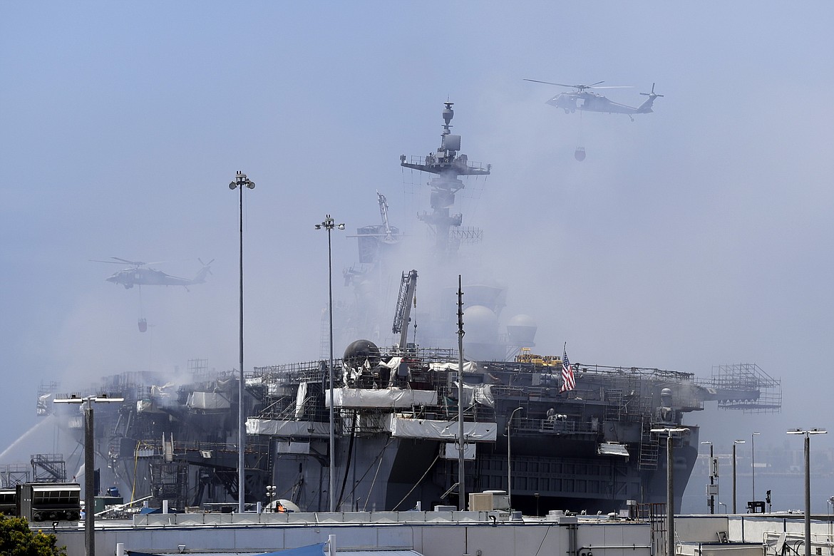 Helicopters approach the USS Bonhomme Richard as crews fight the fire Monday, July 13, 2020, in San Diego. Fire crews continue to battle the blaze Monday after 21 people suffered minor injuries in an explosion and fire Sunday on board the USS Bonhomme Richard at Naval Base San Diego. (AP Photo/Gregory Bull)