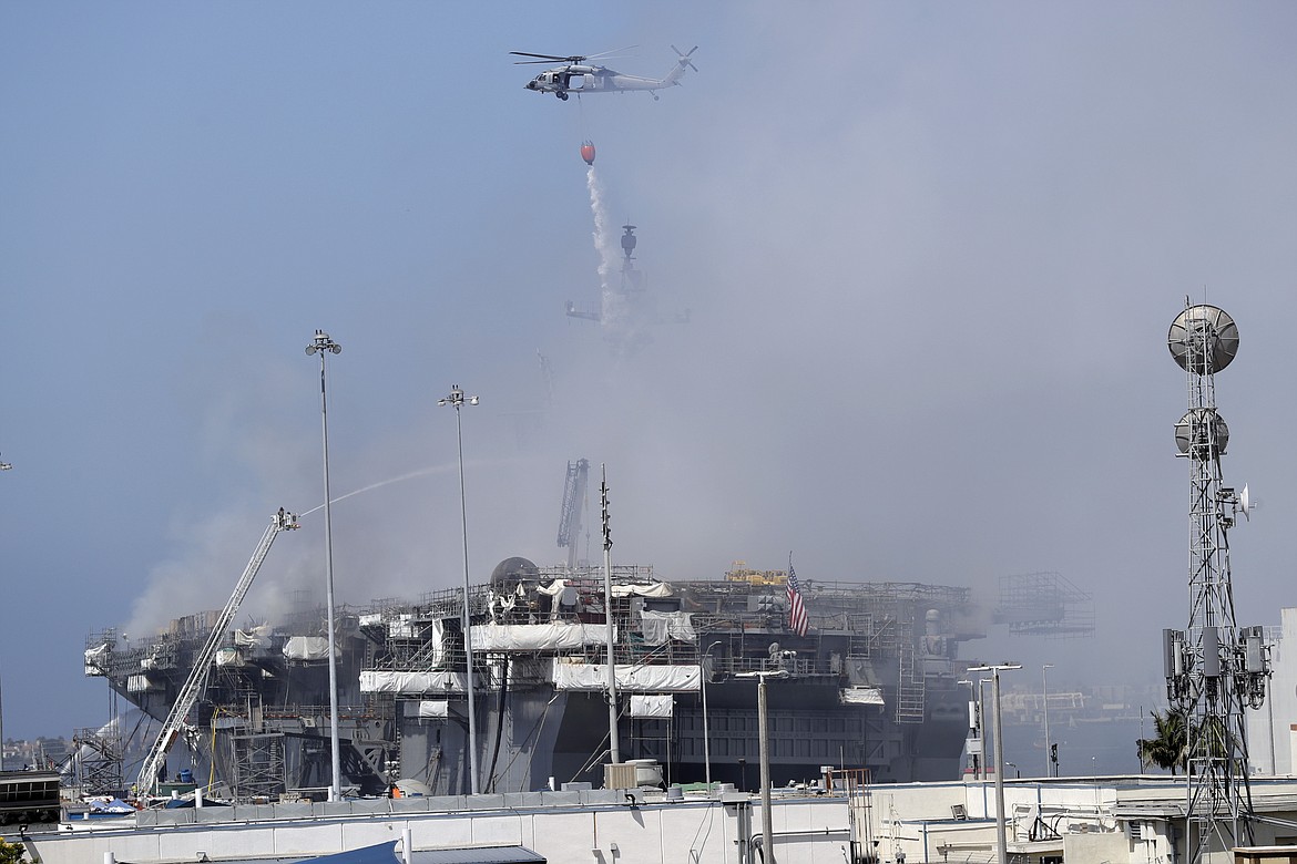 A helicopter drops water on the USS Bonhomme Richard, Monday, July 13, 2020, in San Diego. Fire crews continue to battle the blaze Monday after 21 people suffered minor injuries in an explosion and fire Sunday on board the USS Bonhomme Richard at Naval Base San Diego. (AP Photo/Gregory Bull)