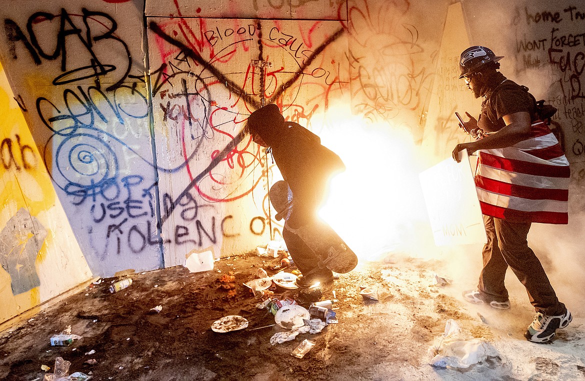 Black Lives Matter protesters try to extinguish a fire set by fellow protesters at the Mark O. Hatfield United States Courthouse on July 22, 2020, in Portland, Ore. (AP Photo/Noah Berger)