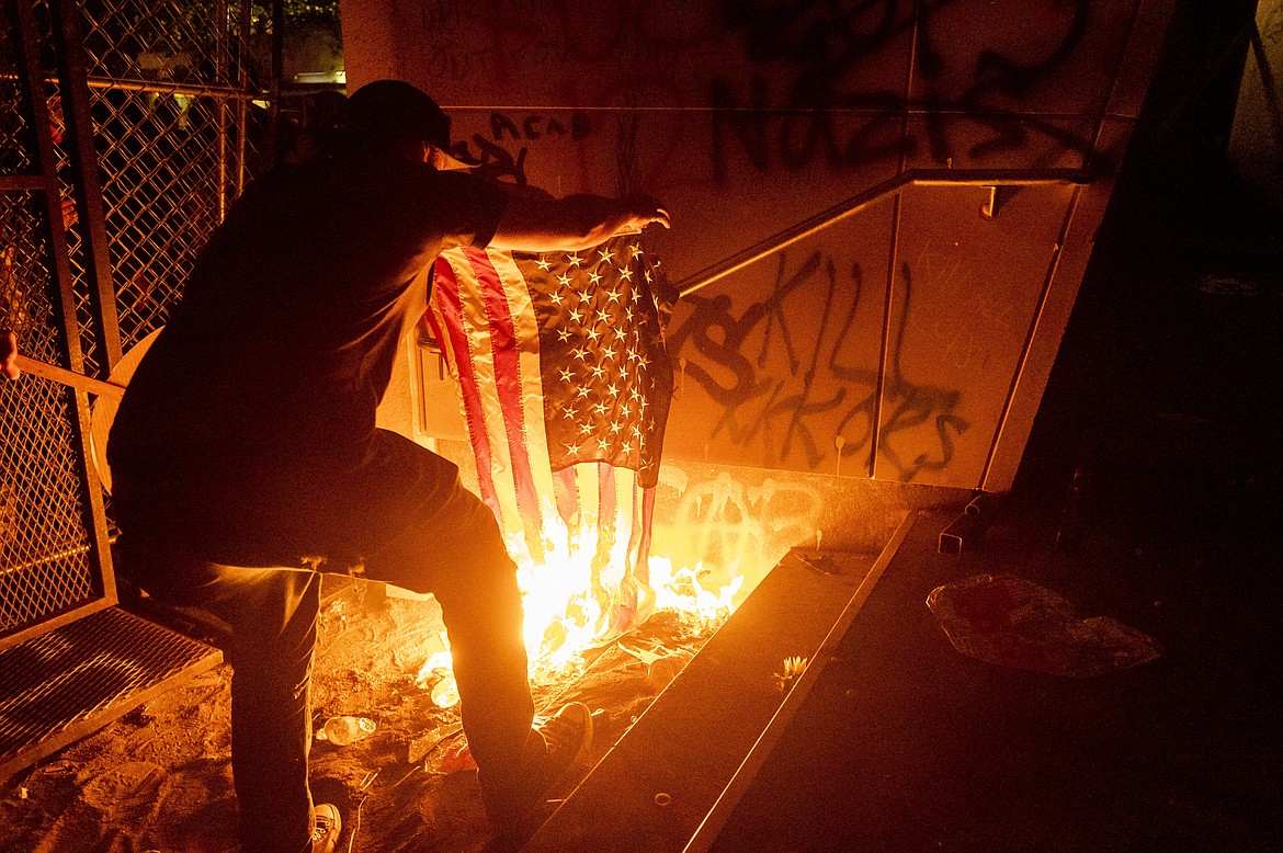 A Black Lives Matter protester burns an American flag outside the Mark O. Hatfield United States Courthouse on Monday, July 20, 2020, in Portland, Ore.  (AP Photo/Noah Berger)