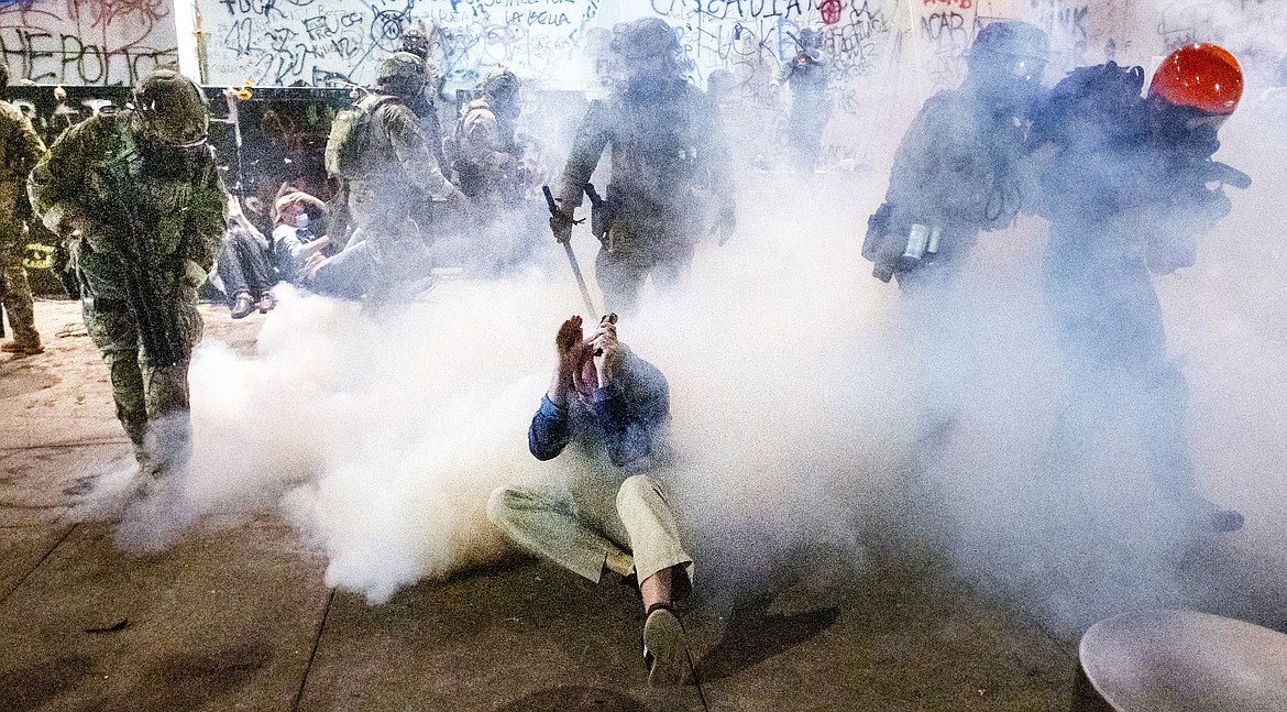 EDS NOTE: OBSCENITY ON WALL - Federal officers use chemical irritants and crowd control munitions to disperse Black Lives Matter protesters outside the Mark O. Hatfield United States Courthouse on July 22, 2020, in Portland, Ore. (AP Photo/Noah Berger)