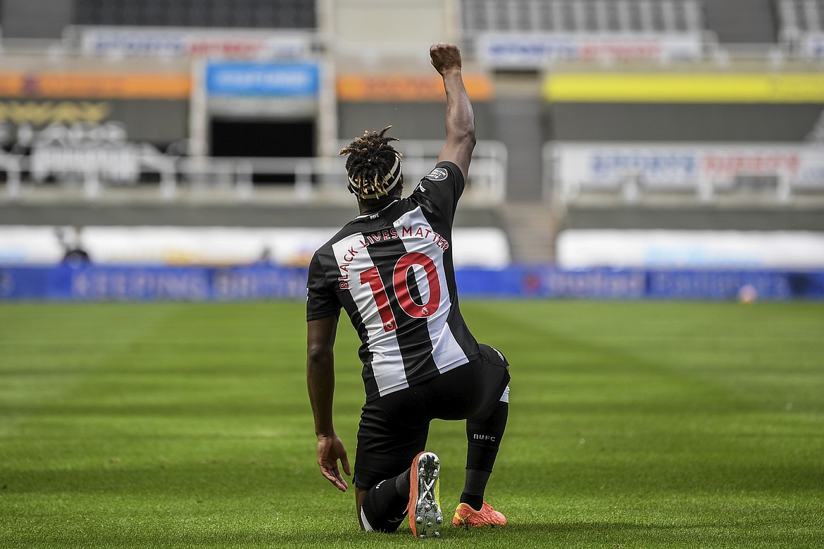 Newcastle's Allan Saint-Maximin takes a knee and raises his fist in the air as he celebrates his goal during the English Premier League soccer match between Newcastle United and Sheffield United at St James' Park stadium in NewCastle, England, Sunday, June 21, 2020. (Michael Regan/Pool via AP)