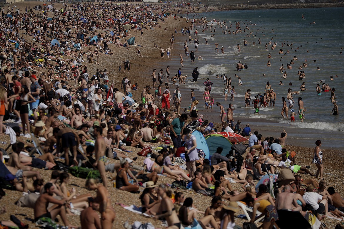 On Britain's hottest day of the year so far with temperatures reaching 32.6 degrees Celsius (90 degrees Fahrenheit) at Heathrow airport, people relax on Brighton Beach in Brighton, England, Wednesday, June 24, 2020. The government announced Tuesday that from July 4 social-distancing rules will be relaxed. People will be advised to stay at least 1 meter (3 feet) apart from others, rather than requiring 2 meters - as long as they take other measures to reduce transmission of the virus, such as wearing a mask in enclosed spaces. (AP Photo/Matt Dunham)