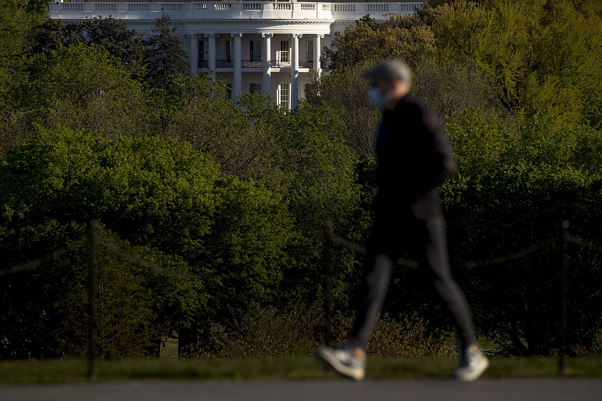 The White House is visible as a man wearing a mask makes his way across the National Mall, Wednesday, April 22, 2020, in Washington. Amid pockets of attention-grabbing protests, a new survey finds Americans remain overwhelming in favor of stay-at-home orders and other efforts to slow the spread of coronavirus. (AP Photo/Andrew Harnik)