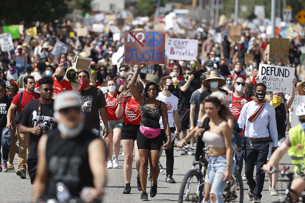 FILE - In this Saturday, June 27, 2020, file photo, demonstrators march down Sable Boulevard during a rally and march over the death of 23-year-old Elijah McClain, in Aurora, Colo. One of the police officers investigated over photographs connected with McClain's death has resigned, Aurora police said Thursday, July 2, 2020. (AP Photo/David Zalubowski, File)